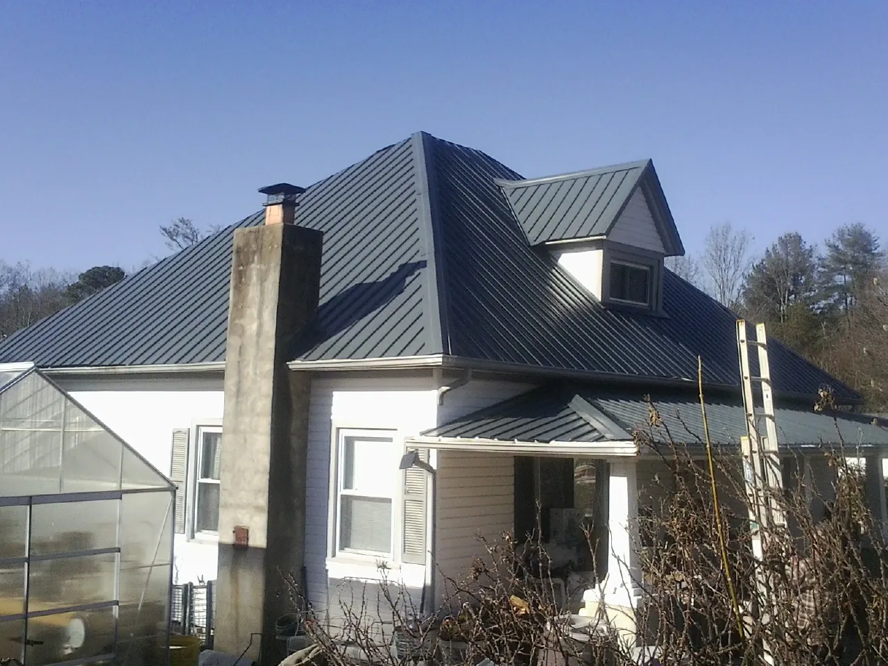 Dark blue standing seam metal roof on a white farmhouse with dormer — Slate & Tile Roof Repair by Roofing Brothers in Birdsboro