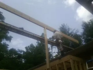 Carpenter setting a ridge beam over a new addition frame — Ice Dam Removal by Roofing Brothers in Birdsboro