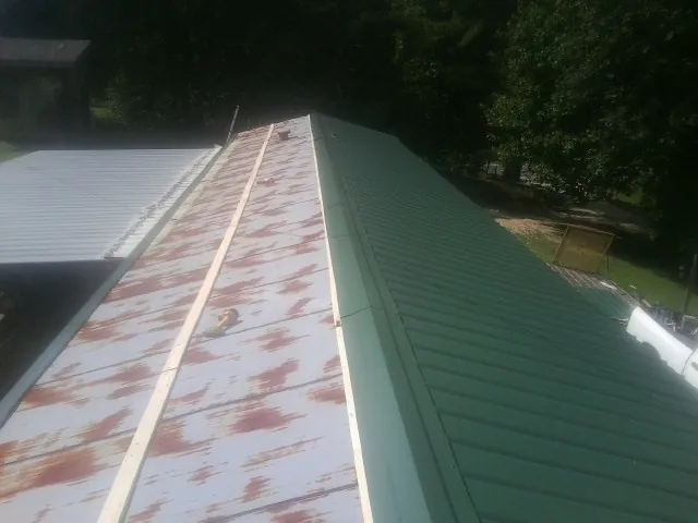 Old rusted panels beside newly installed green metal roofing — Wind Damage Roof Repair by Roofing Brothers in Birdsboro