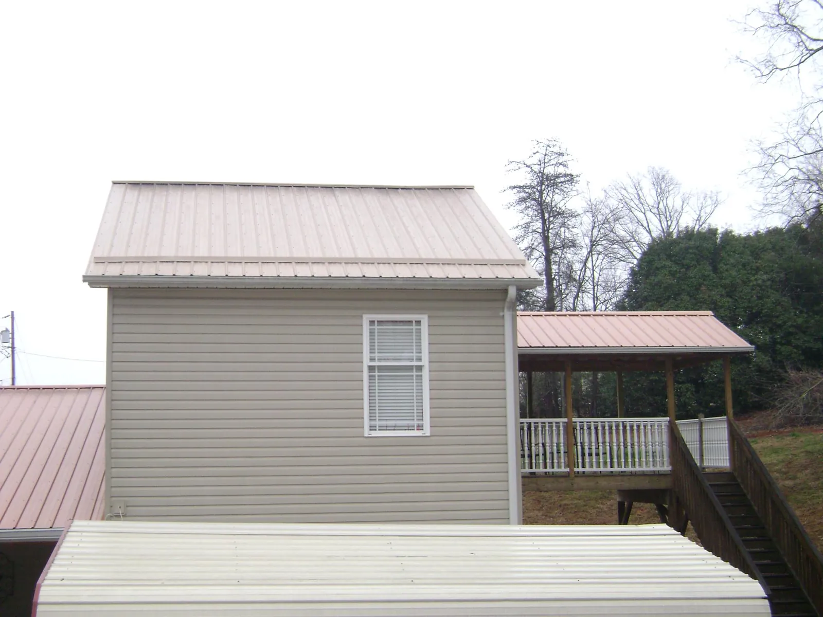 Tan metal roofs on a two story addition and attached porch, from a Roof Replacement job in Birdsboro