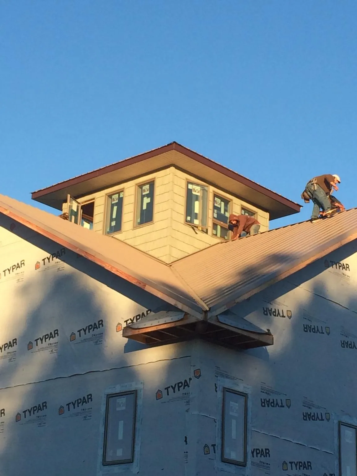 Roofers working around a rooftop cupola on a new metal roof at sunset — Roof Waterproofing in Birdsboro by Roofing Brothers
